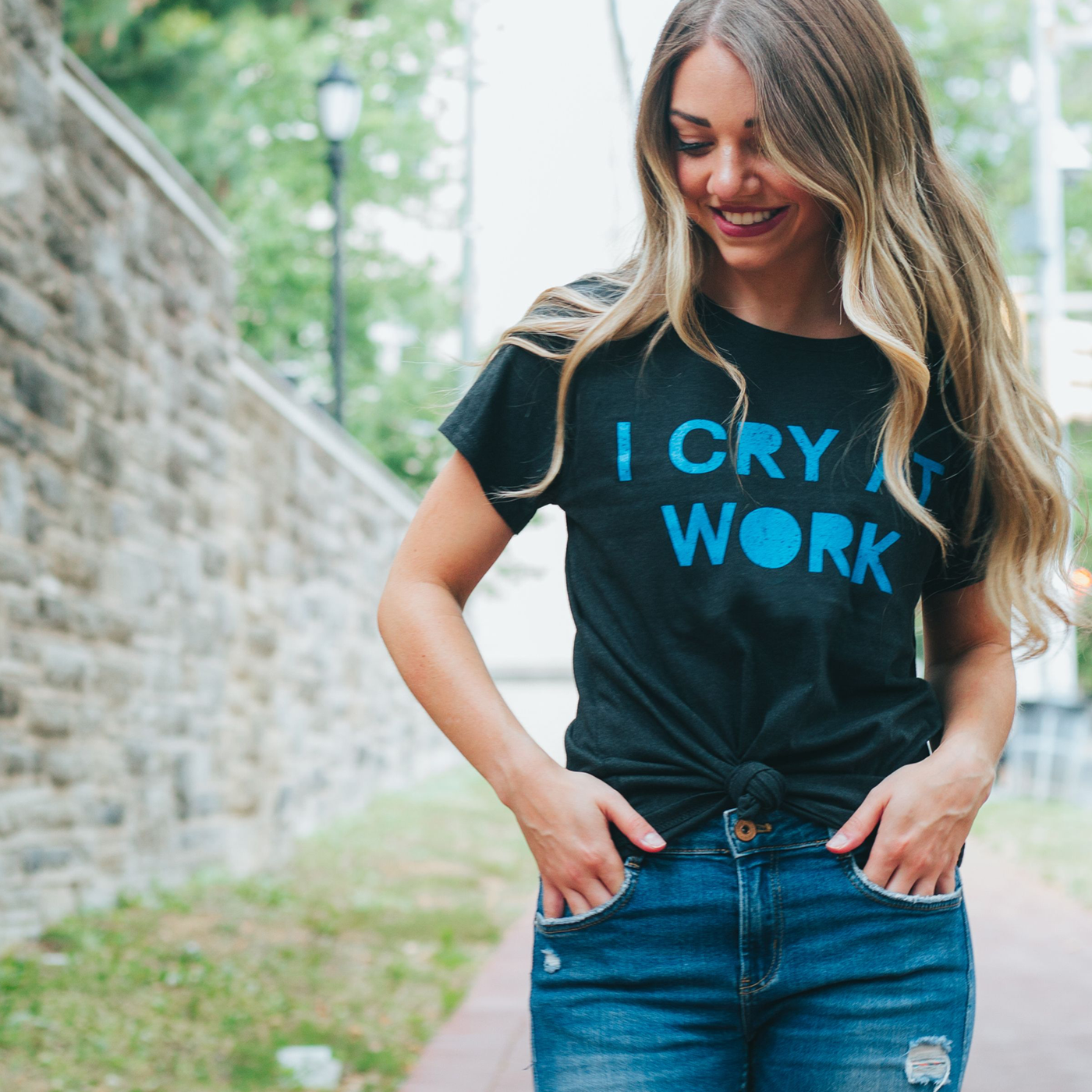 Blonde woman wearing a grey shirt with a blue print out that say I cry at work on it